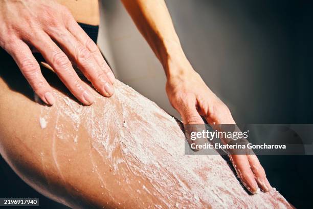close-up of hands applying lotion on skin in modern shower setting - massageöl stock-fotos und bilder