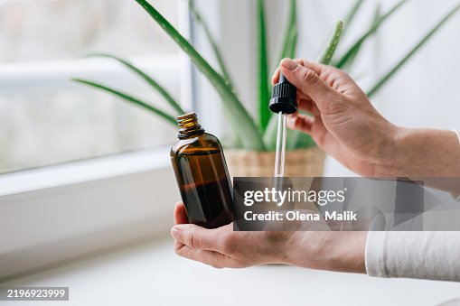 Woman Holding Glass Dropper Bottle with Natural Essential Oil Woman Holding Glass Dropper Bottle with Natural Essential Oil