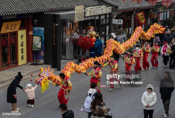 Young girl reaches to touch the head during a traditional dragon dance performed for luck and good fortune, during Chinese Lunar New Year and Spring...