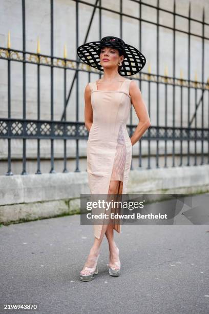 Gessica Kayane wears black cutout design Tamara Ralph hat, silver earrings, cream high slit corset sleeveless Tamara Ralph midi dress, transparent...