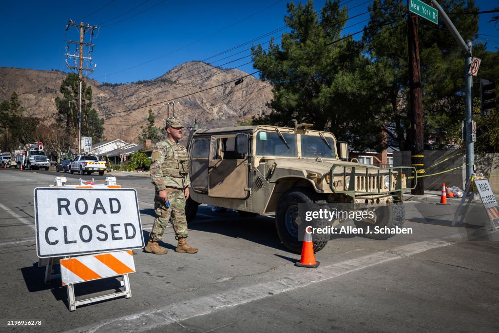 A firefighter views signs at a home that was spared from the Eaton fire, where the homeowner thanks first responders and warns looters that they will be shot in Altadena