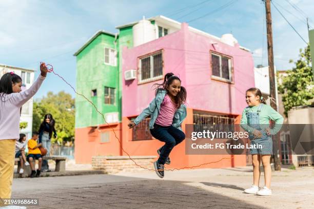 child girls playing of jumping rope outdoors - touwtje springen stockfoto's en -beelden