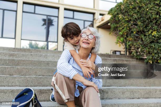 abuela y nieto abrazados en los escalones de la escuela - nietos fotografías e imágenes de stock