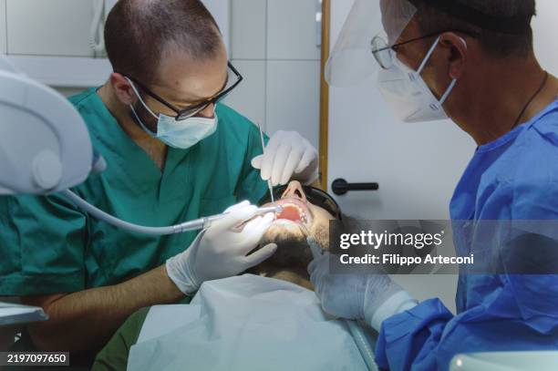 dentist working with drill on patient mouth with assistant - dental drill stock pictures, royalty-free photos & images