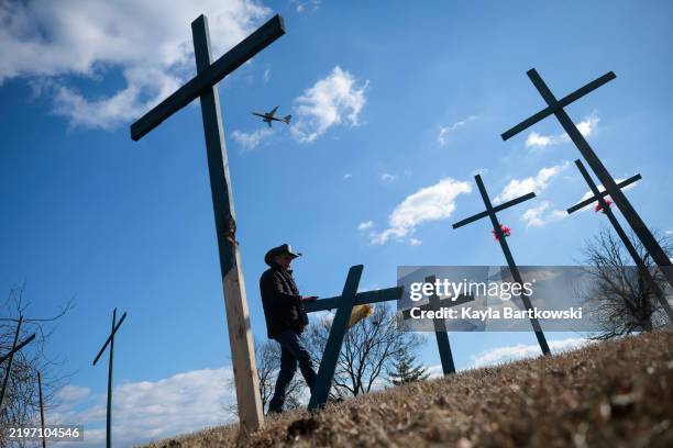 An airplane takes off from Reagan National Airport as Roberto Marquez from Dallas, Texas, builds crosses for a memorial for the victims of the midair...