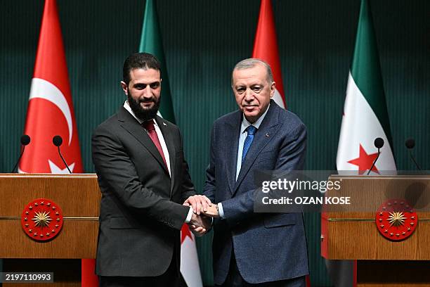 Turkish President Recep Tayyip Erdogan and Syria's interim president Ahmed al-Sharaa shake hands during a joint press conference following their...