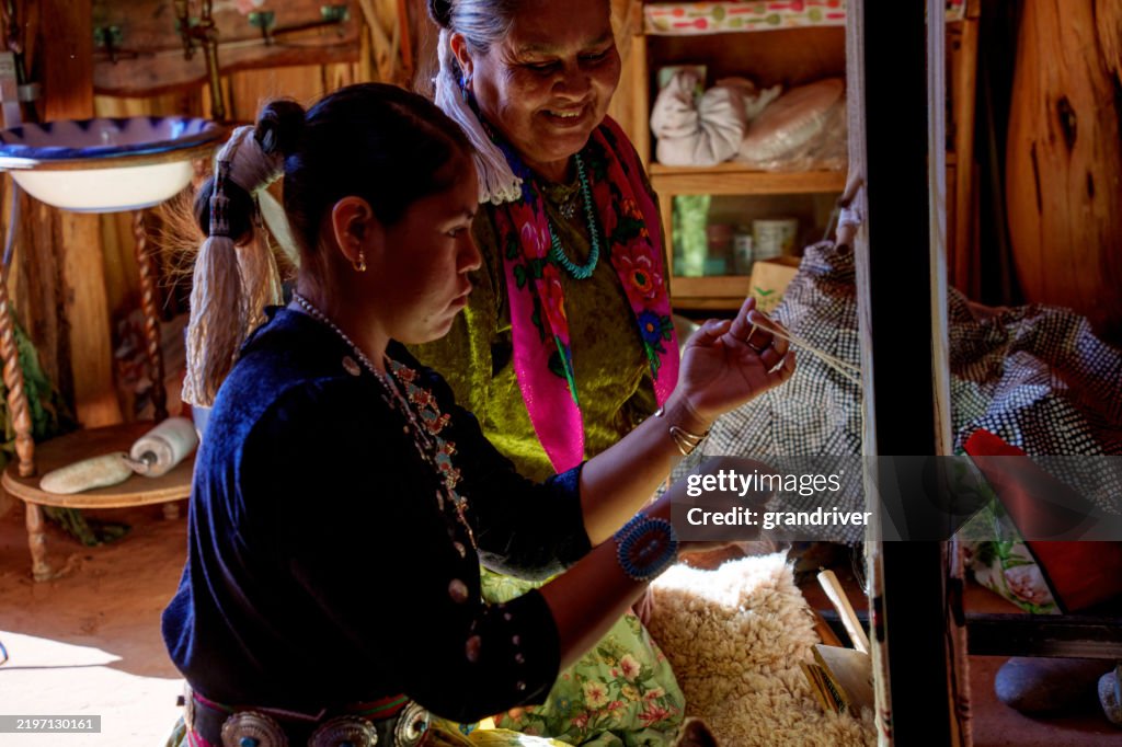 Traditional Elderly Navajo Woman Working to Make an Authentic Blanket on a Loom, Teaching Her Granddaughter and Spending Quality Time in a Traditional Navajo Hogan in Monument Valley Southern Utah, Northern Arizona