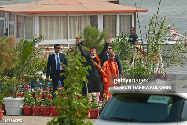 India's Prime Minister Narendra Modi waves next to the chief minister of Uttar Pradesh state Yogi Adityanath, after taking a holy dip in the sacred...