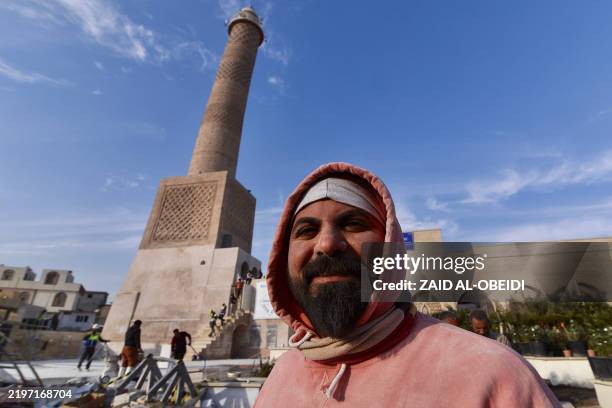Builder poses for a picture during the ongoing reconstruction of the historic Great Mosque of al-Nuri, whose "Al-Hadba" leaning minaret which dates...