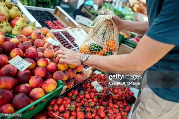 hombre mayor comprando frutas en un mercado de agricultores - bolsa reutilizable fotografías e imágenes de stock