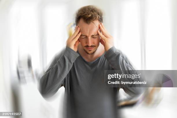 hombre con vértigo que tiene fuertes dolores de cabeza - física fotografías e imágenes de stock