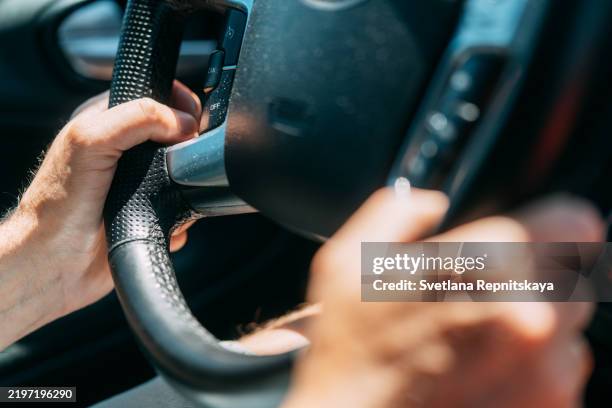 driver adjusting cruise control while driving modern car - convenienza foto e immagini stock
