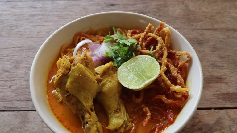 https://media.gettyimages.com/id/2197201578/video/chicken-khao-soi-with-vegetable-side-dishes-on-a-white-plate-on-a-wooden-table-khao-soi-is-a.jpg?b=1&s=640x640&k=20&c=mUgryIu3SWdEBzV9kSIyp4snqFFdkFWx38iXQWBFq9s=