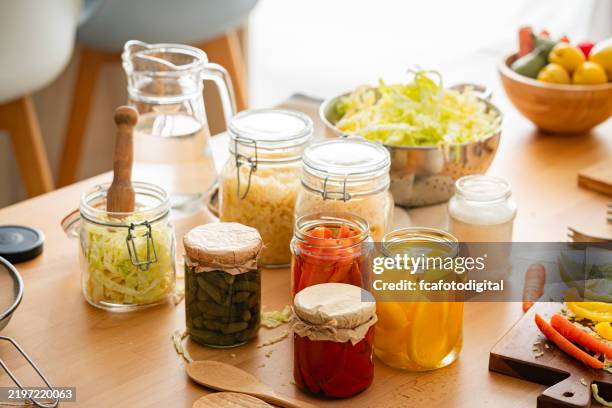 various fermented and pickled vegetables in glass jars on kitchen table. high anle view - probiotic stock pictures, royalty-free photos & images