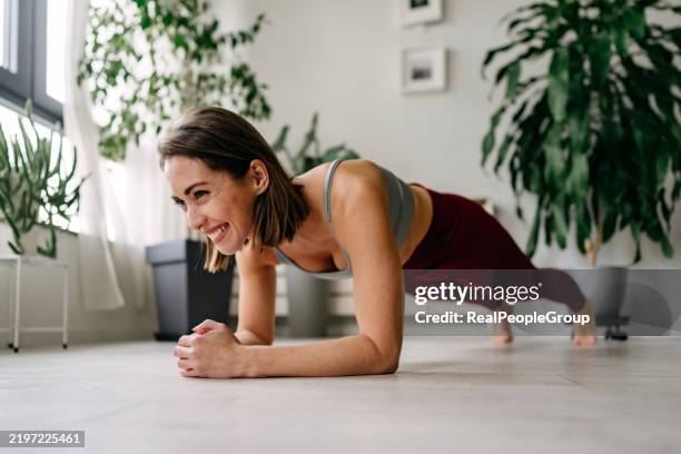 donna sorridente che fa esercizio di plank a casa - muscolo addominale foto e immagini stock