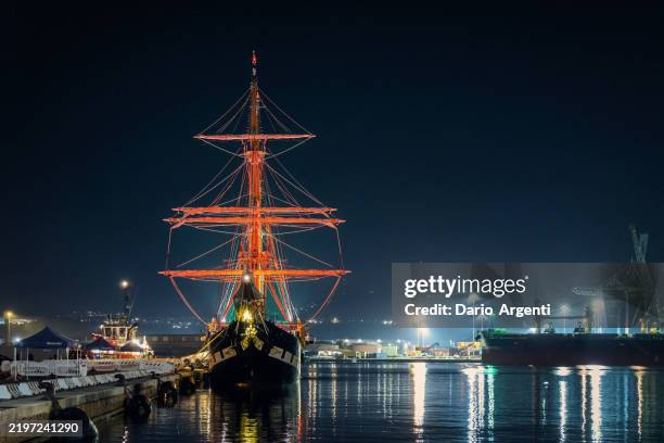 night photography of the italian navy sailing ship palinuro, moored in the port in the city of ancona in italy. - military ship dock stock pictures, royalty-free photos & images