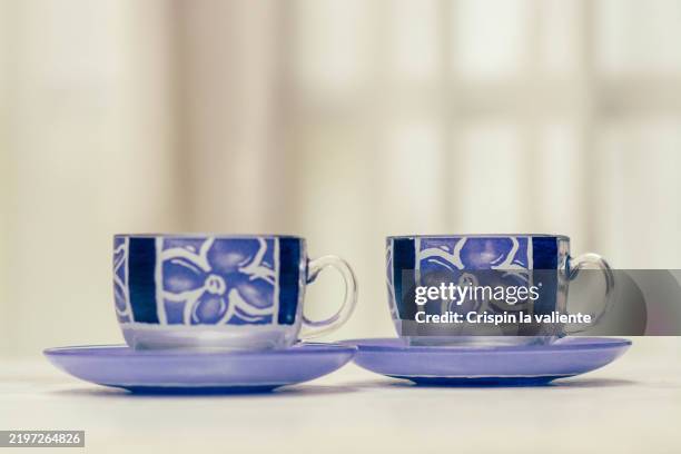 two empty purple teacups with floral design resting on saucers - porcelana china fotografías e imágenes de stock