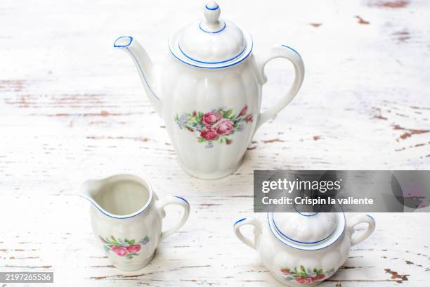 porcelain tea set with floral decoration on rustic white table - jarra de leche fotografías e imágenes de stock