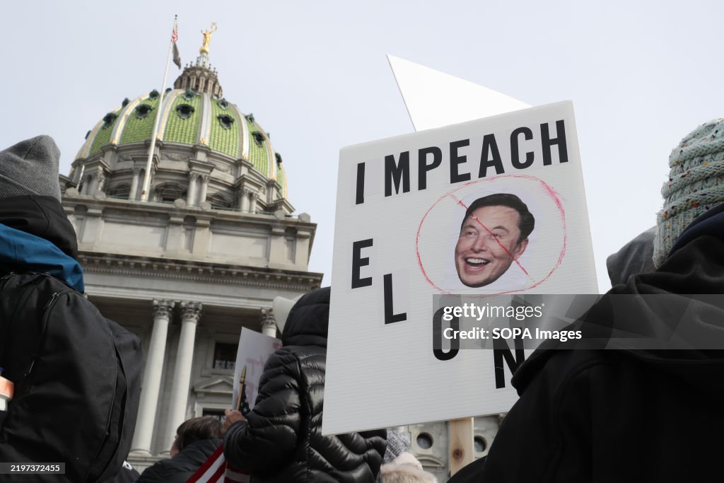 A protester holds an anti-Musk placard outside of the...
