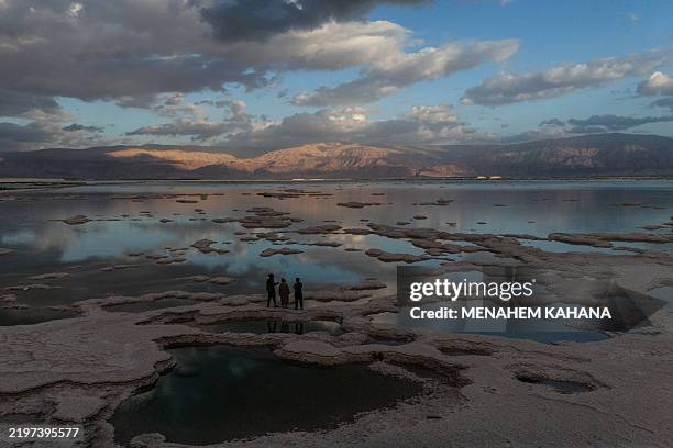 People walk on patterns formed by crystalized minerals on the surface of evaporation ponds in the Dead Sea, near the Israeli resort of Ein Bokek on...