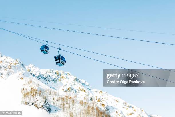 cable cars transporting skiers up snowy mountain on sunny day - stazione sciistica foto e immagini stock