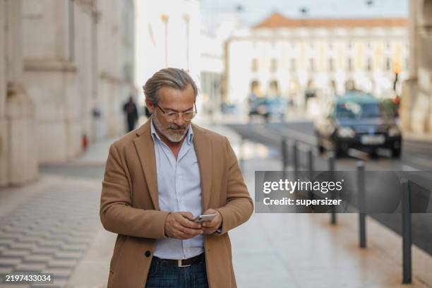 confident elderly man texting on the city street. - meaningful stock pictures, royalty-free photos & images