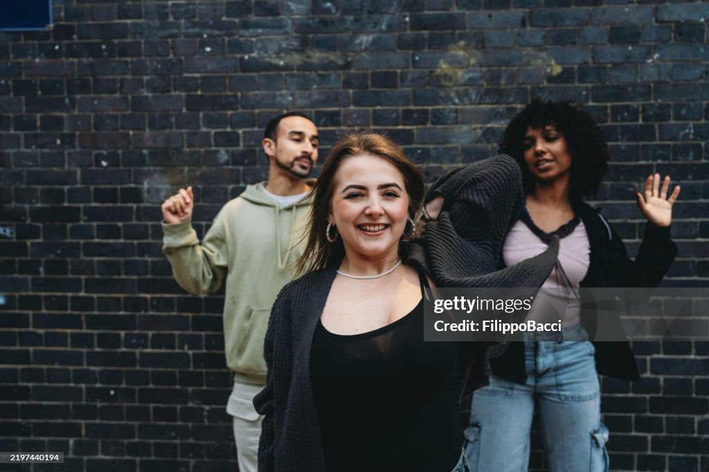 Young friends dancing and having fun against a brick wall