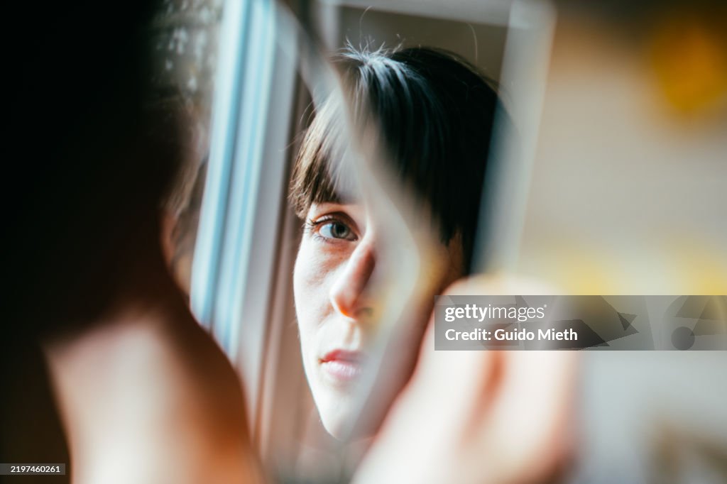 Portrait of a beautiful woman looking into a broken mirror.