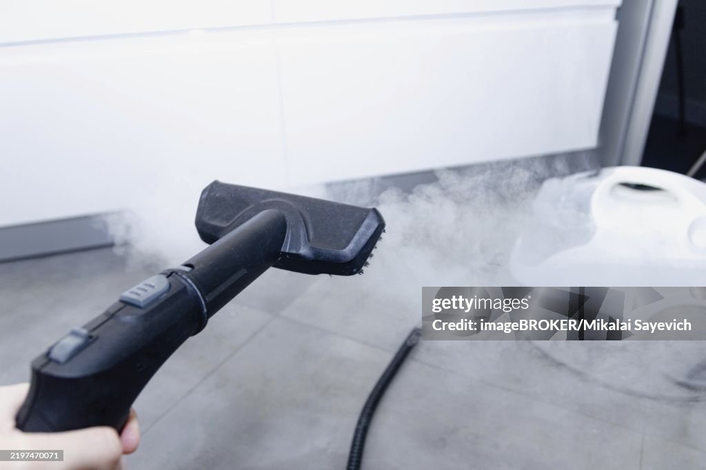Steam cleaner hovering over a tile floor releasing steam