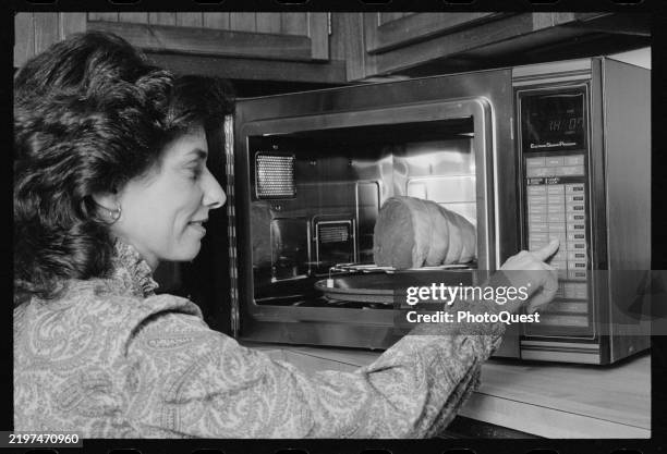 View of an unidentified woman as she selects microwave buttons to cook a cut of meat, July 12, 1983.