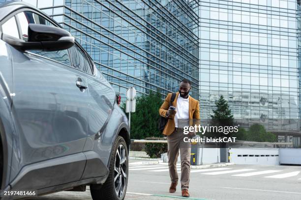 a man approaches his car in the parking lot in front of an office building - parking stock pictures, royalty-free photos & images