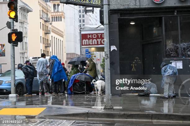 Homeless people are seen on a sidewalk during heavy rain in Tenderloin district of San Francisco, California, United States on February 6, 2025.