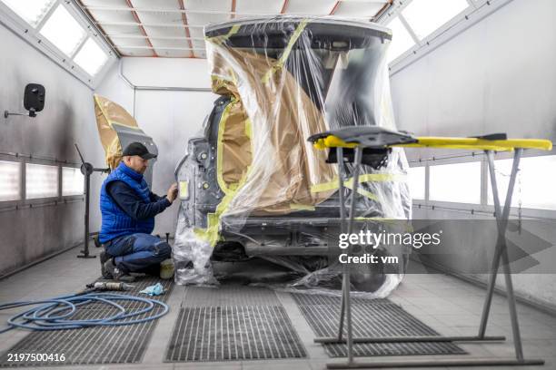 caucasian male inspecting car paintwork in workshop - mid adult stock pictures, royalty-free photos & images