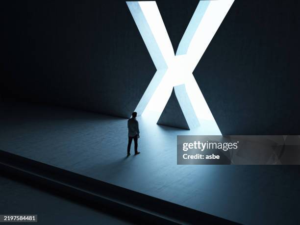 a man entering a hall with stairs through x shaped gate - letra x imagens e fotografias de stock