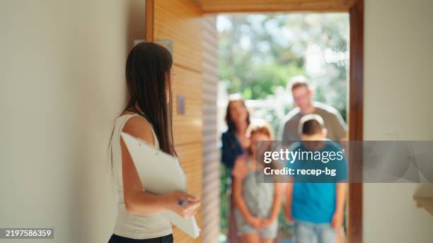 real estate agent leading a family into a bright home - renting stock pictures, royalty-free photos & images