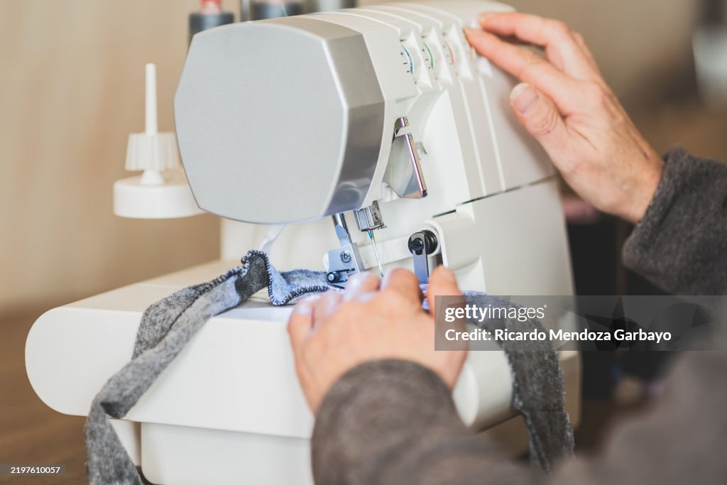 Tailor using a serger sewing machine for overlock stitching on fabric