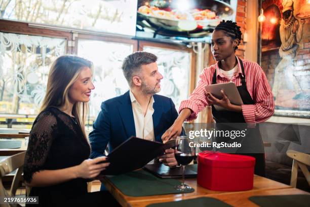 camarera del elegante restaurante recomendando a una pareja qué pedir - pedir matrimonio fotografías e imágenes de stock