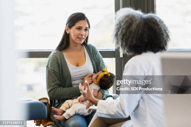 une mère et un médecin discutent de la santé de leur bébé en clinique - pédiatre photos et images de collection