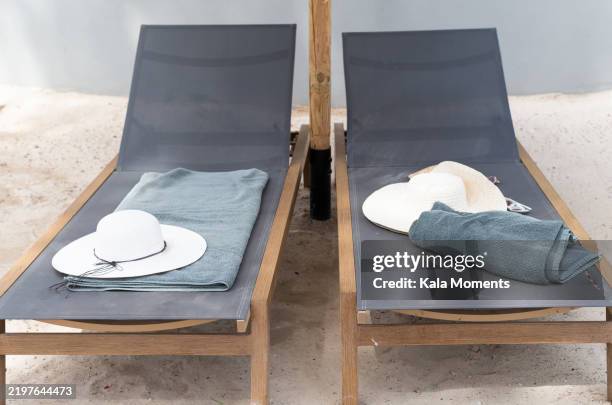 two sunbeds with towels and hats inviting for relaxation by the pool - sedia a sdraio foto e immagini stock