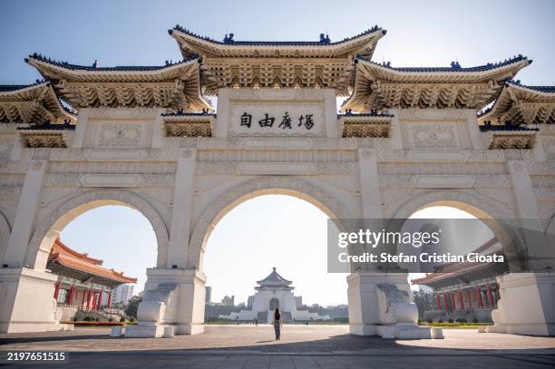 girl exploring the national chiang kai-shek memorial hall. she walks through the archway at liberty square in taipei, taiwan. - taipei stock pictures, royalty-free photos & images