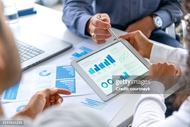 close up of three people looking at financial data with graphs and charts. - datos fotografías e imágenes de stock