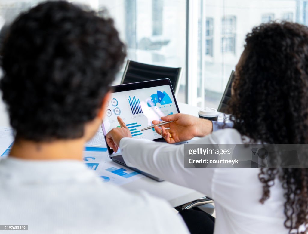 Three people looking at financial data with graphs and charts.