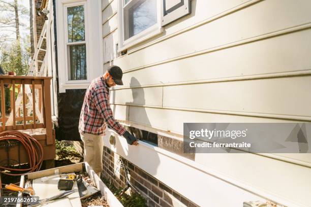 ouvrier du bâtiment réparant le revêtement d’une maison - remplacement photos et images de collection