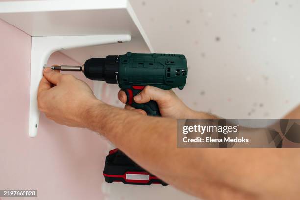 close up of man's hands with screwdriver hanging shelf - renovierung themengebiet stock-fotos und bilder