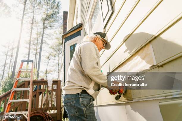 trabajador de la construcción reparando el revestimiento de una casa - revestimiento de paredes fotografías e imágenes de stock