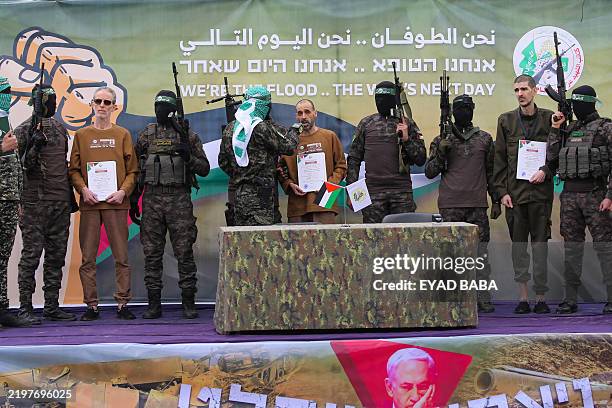 Palestinian Hamas fighters escort Israeli hostages Ohad Ben Ami, Eli Sharabi and Or Levy on a stage before handing them over to a Red Cross team in...