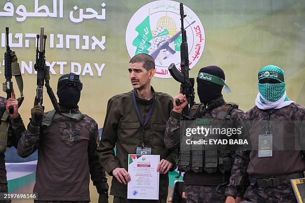 Palestinian Hamas fighters escort Or Levy on a stage before handing him over to a Red Cross team in Deir el-Balah, central Gaza, on February 8 as...