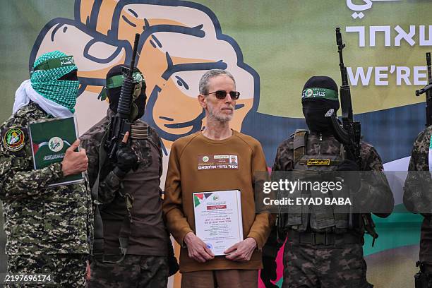 Palestinian Hamas fighters escort Ohad Ben Ami on a stage before handing him over to a Red Cross team in Deir el-Balah, central Gaza, on February 8...