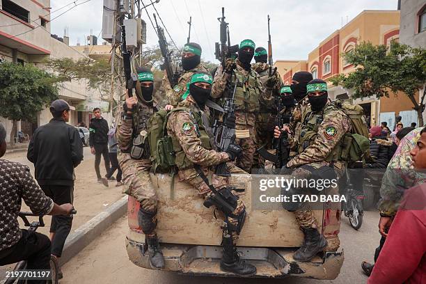 Hamas fighters patrol a street before they handover three Israeli hostages to a Red Cross team in Deir el-Balah, central Gaza, on February 8, 2025....