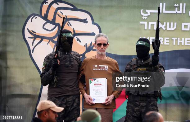 Palestinian Hamas fighters escort Israeli hostages before handing them over to a Red Cross team in Deir el-Balah, central Gaza, on February 8 as part...